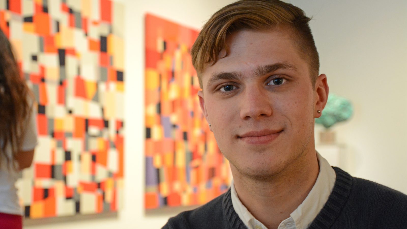 Kyle Canter sits in front of two paintings