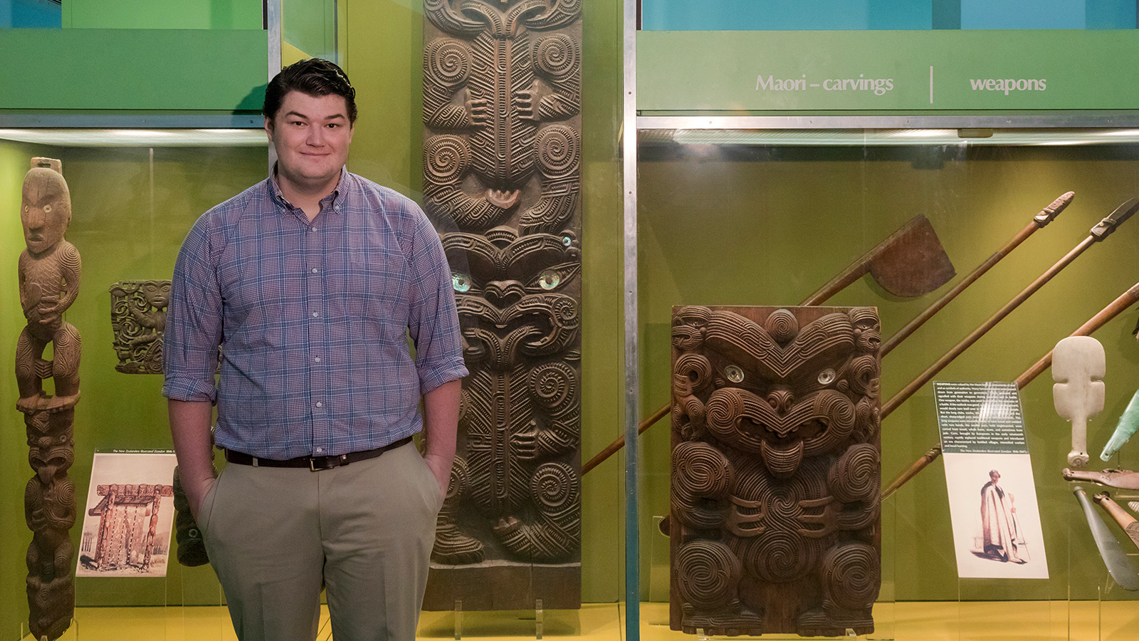 Colin Gravelle stands in front of a case of Maori artifacts.