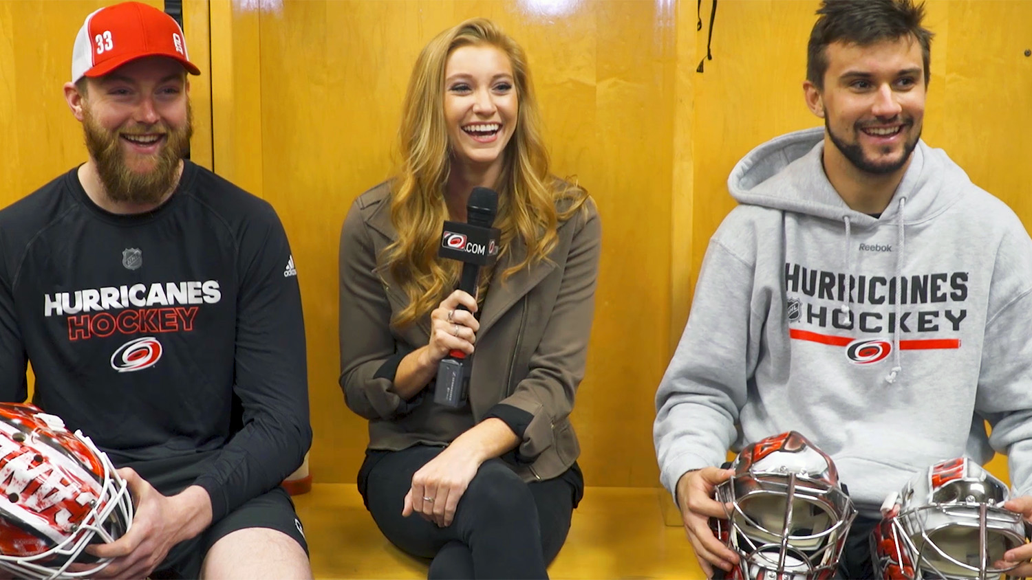 Holding a microphone. Abby Labar interviews two Carolina Hurricanes players