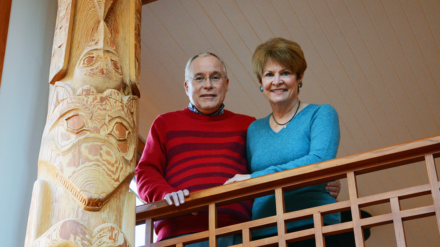 Hesters stand on balcony next to totem pole.