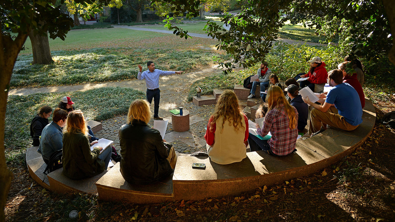 A faculty member addresses students in an outdoor classroom