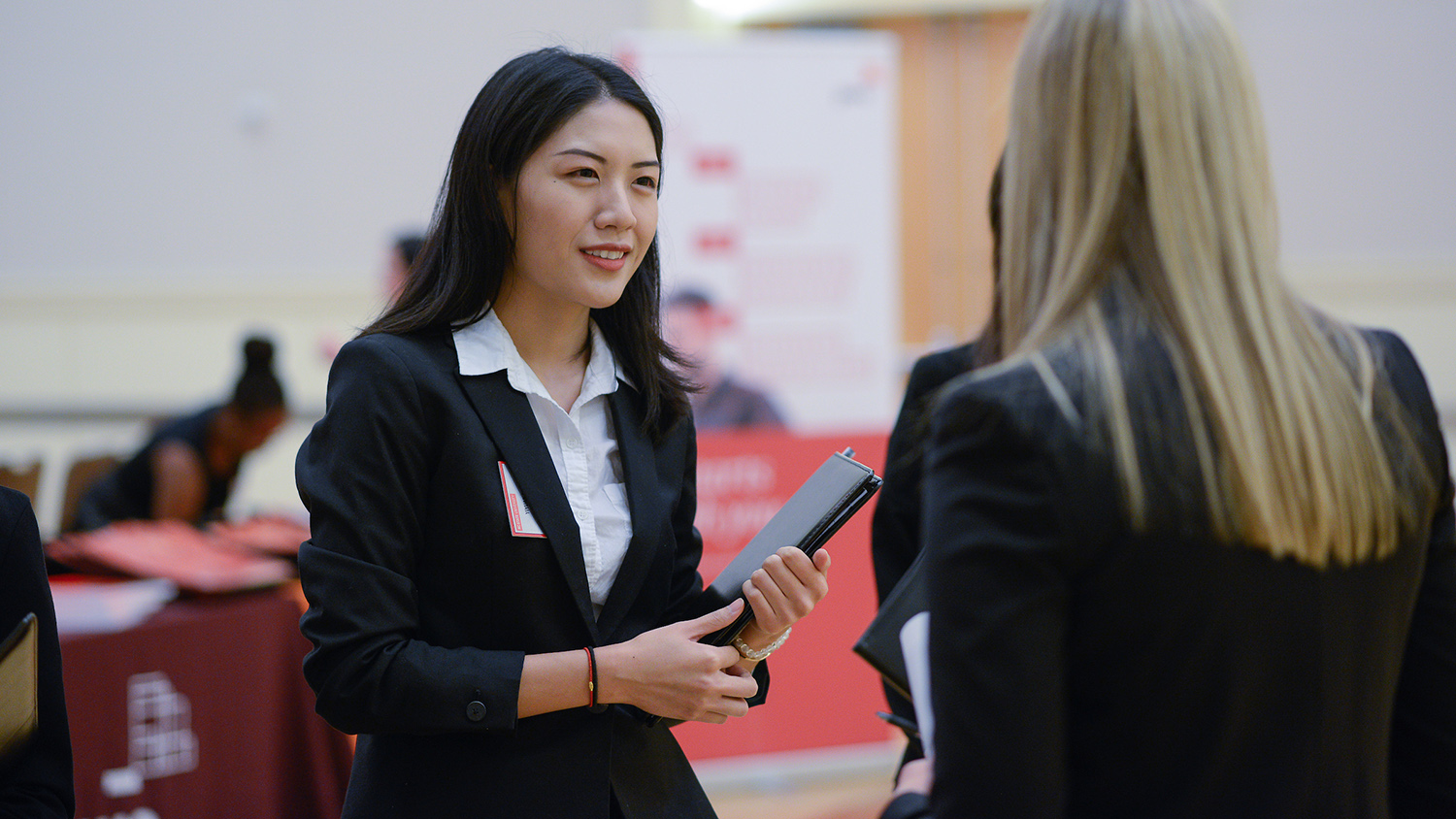 woman holds planner while talking to another woman