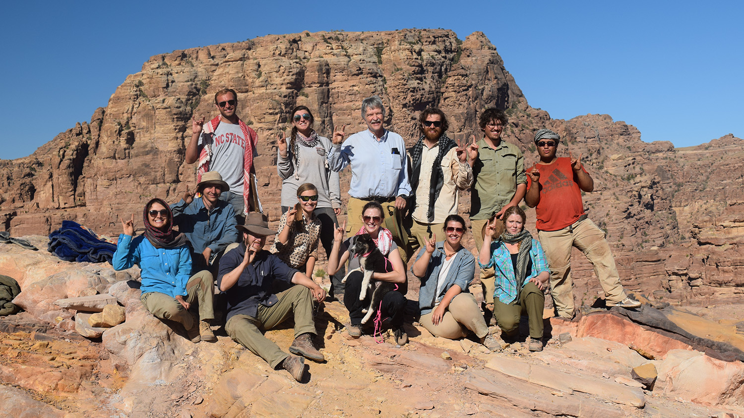 Faculty and student researchers pose on a cliff side in Petra