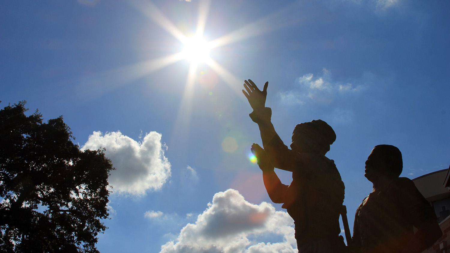 statues of a man and woman silhouetted against the sun