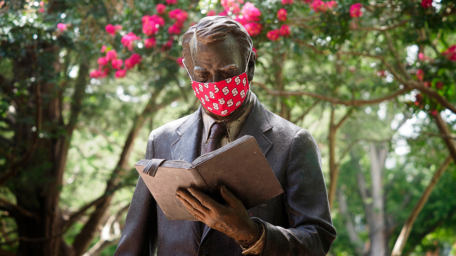 The strolling professor statue dons a protective mask