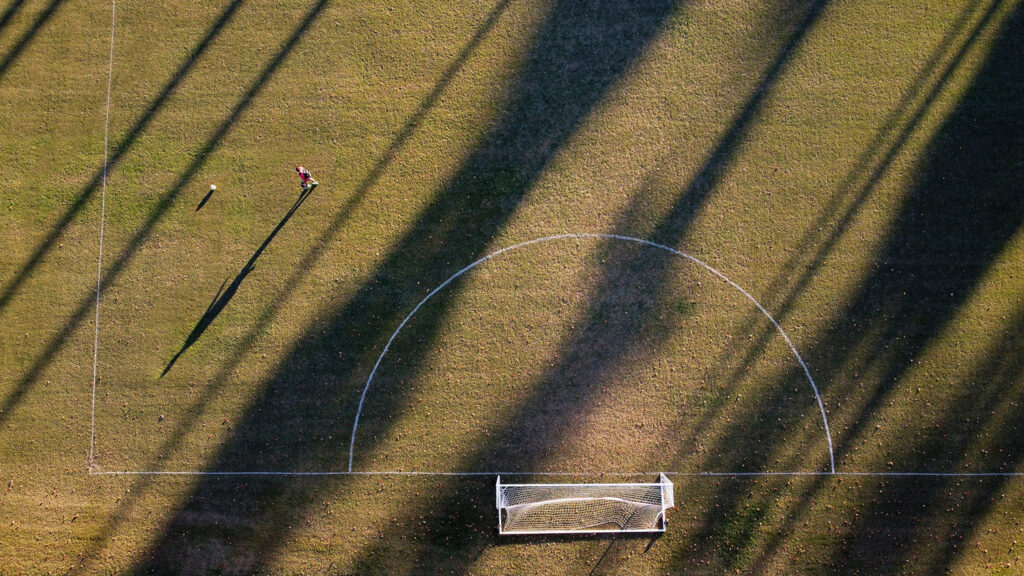 An NC State students kicks a soccer ball 