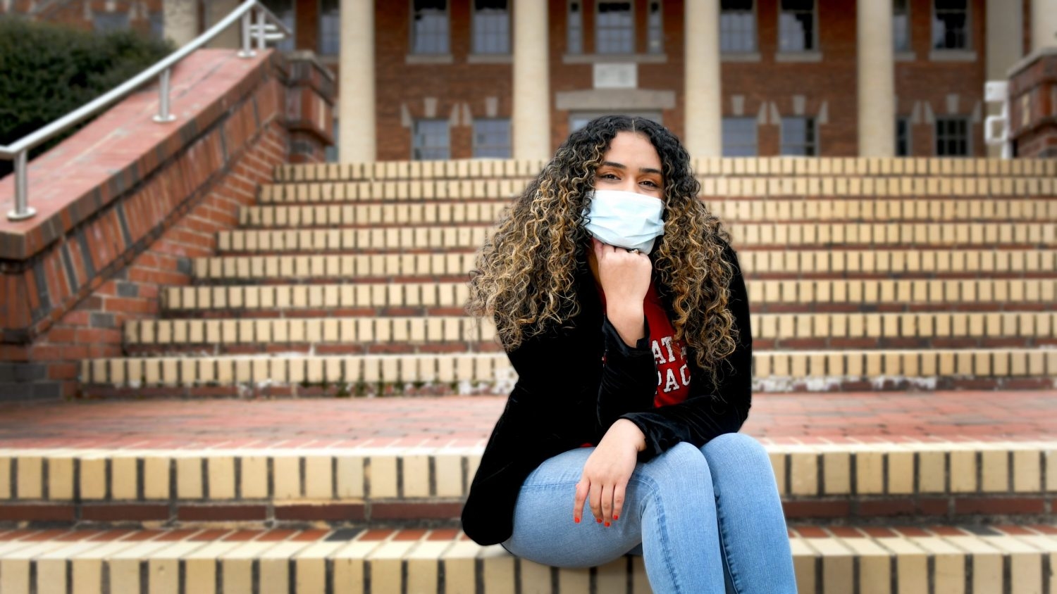 Nataly Vaquez Perez sits on the steps of an NC State building