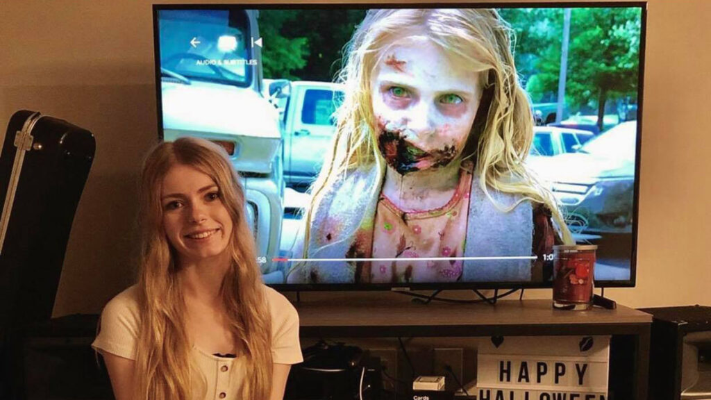 Addy Miller sitting in front of TV with "The Walking Dead"