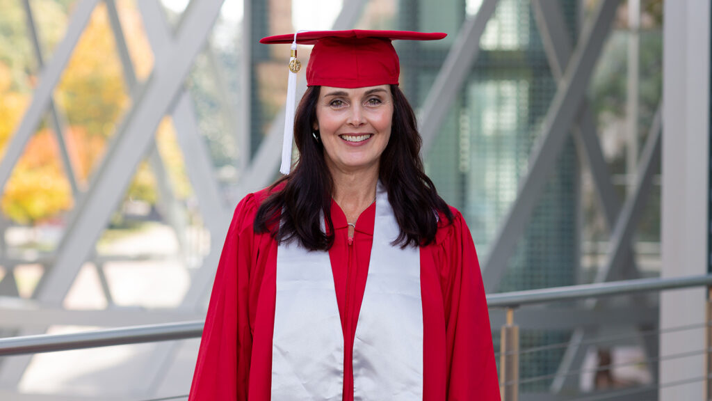 student standing in red graduation regalia