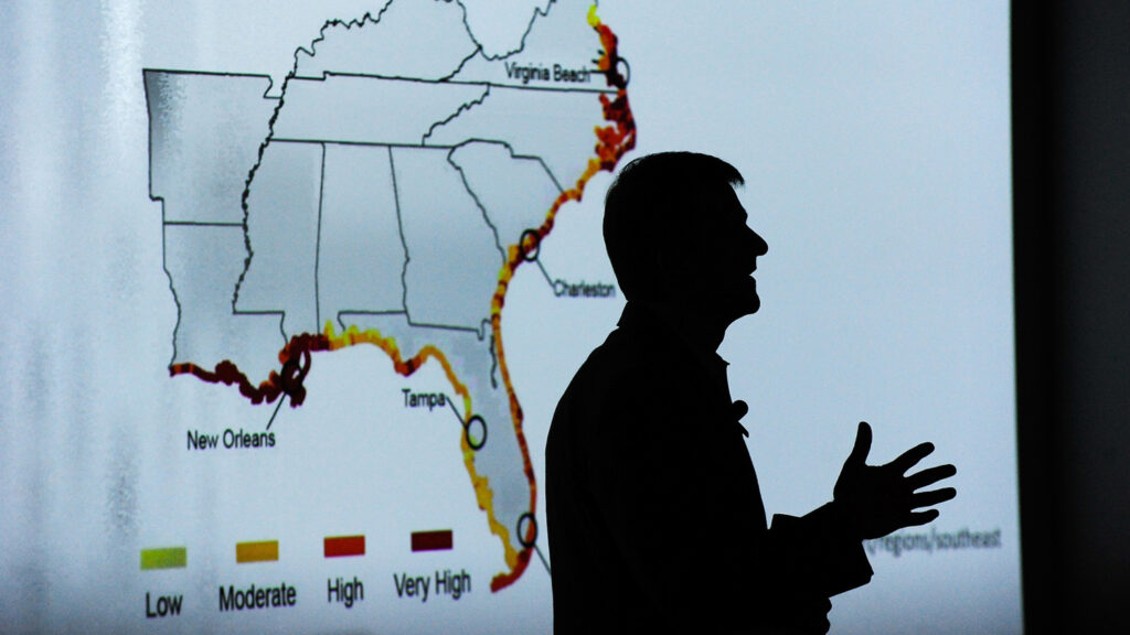 A professor stands in front of a visualization of the southeast united states