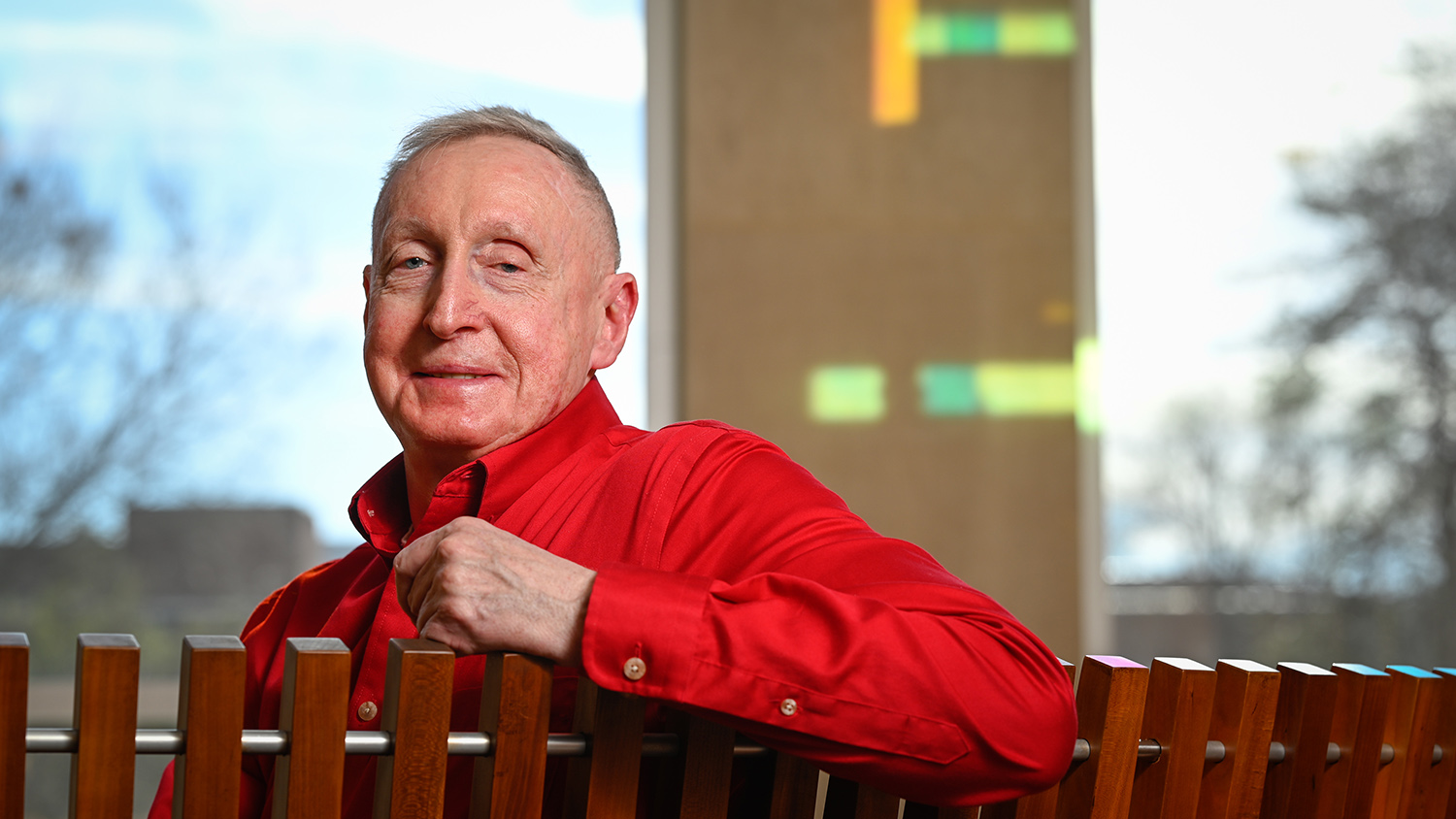 James Sorrell sitting on bench and dressed in red shirt