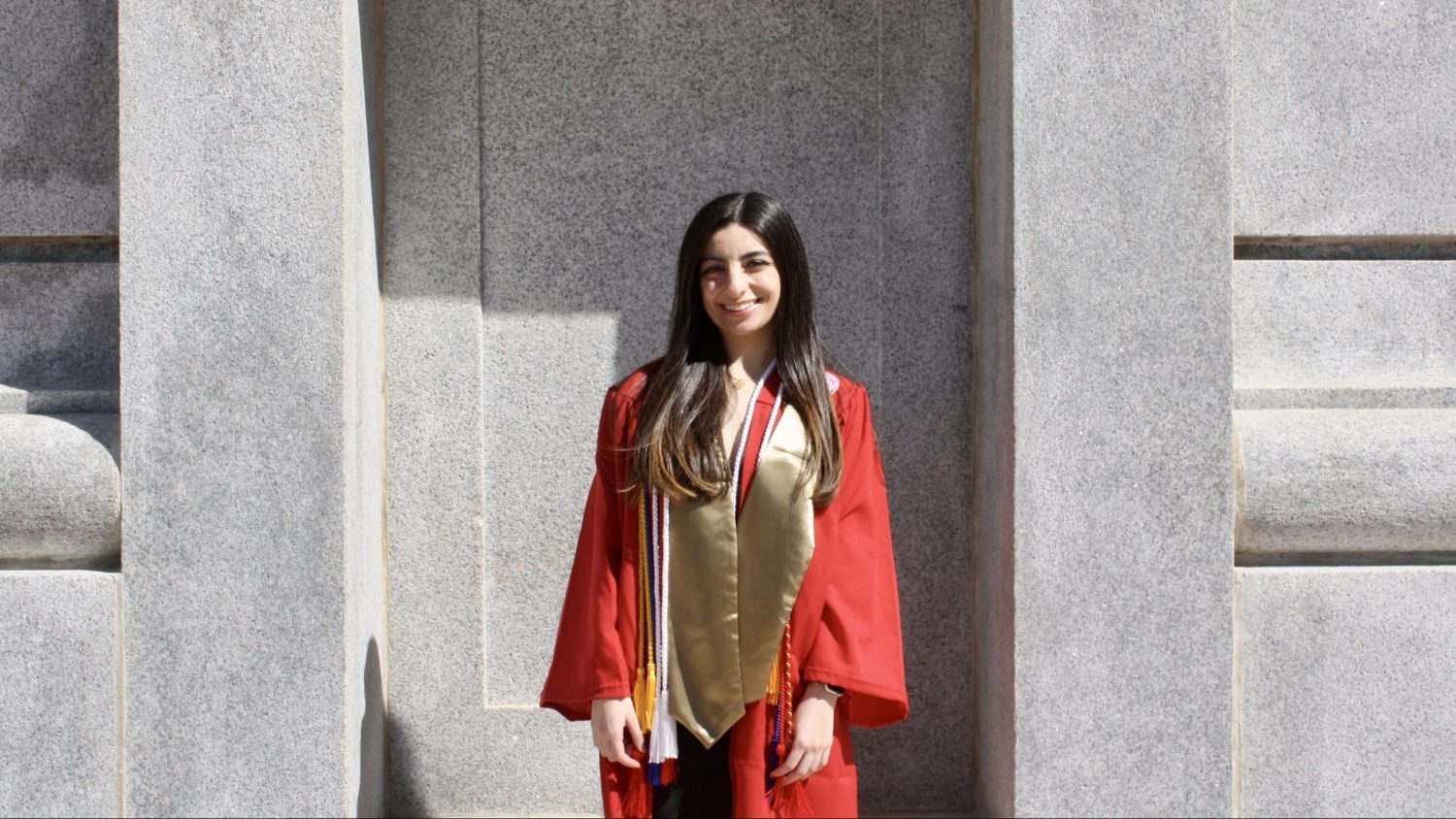 Loujain Al Samara in front of the Belltower in her cap and gown