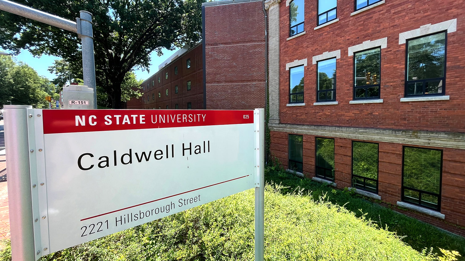 A sign reads, Caldwell Hall, in front of a brick building