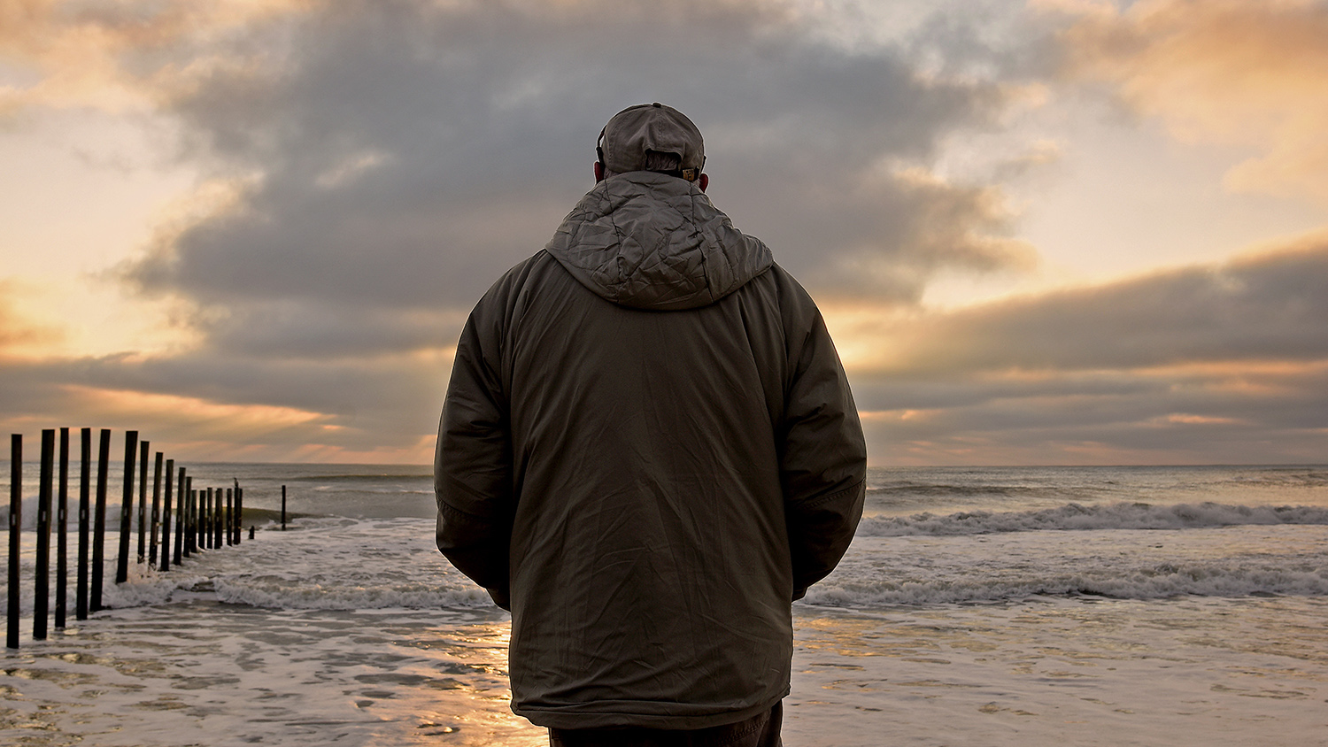 A man stands on a beach, overlooking the ocean