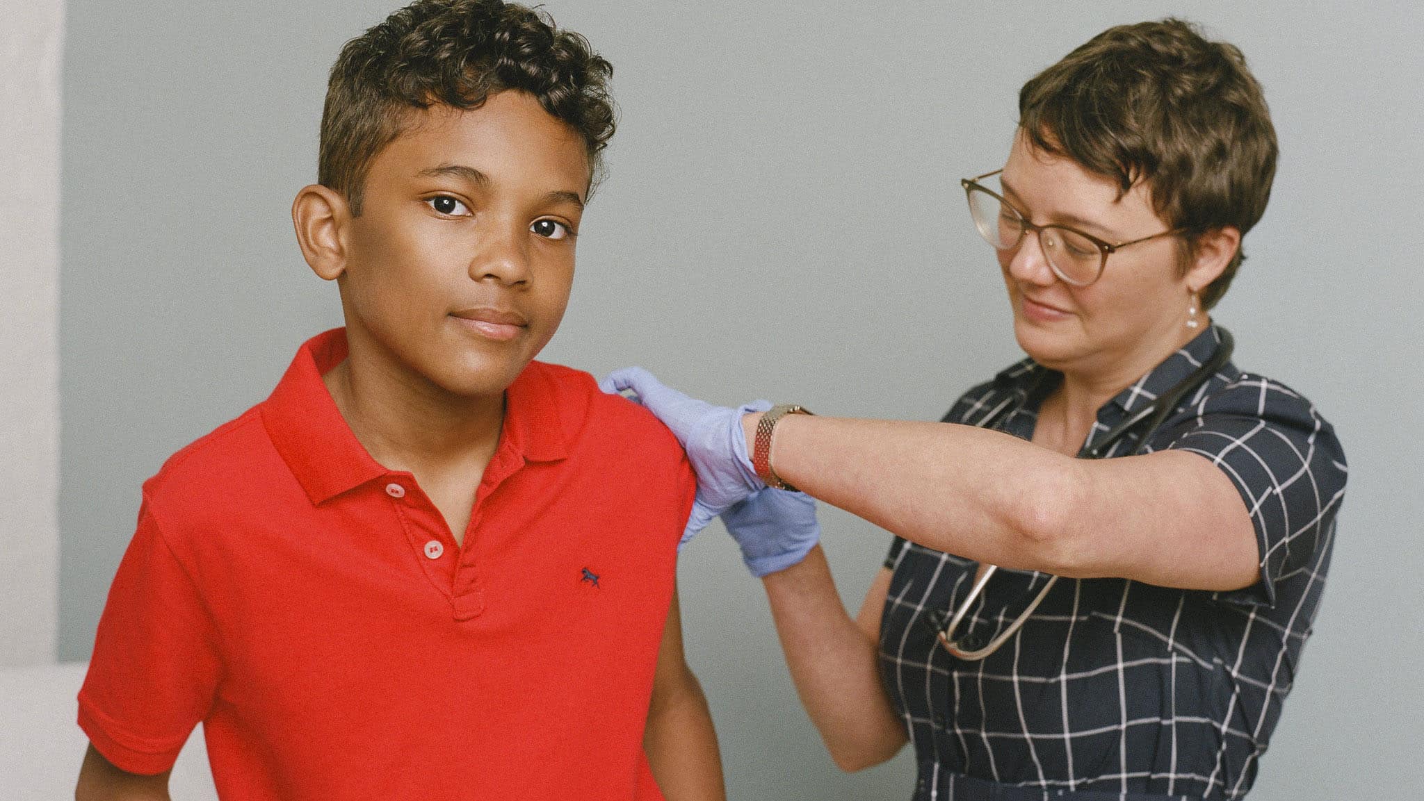boy receives a vaccine shot from a woman
