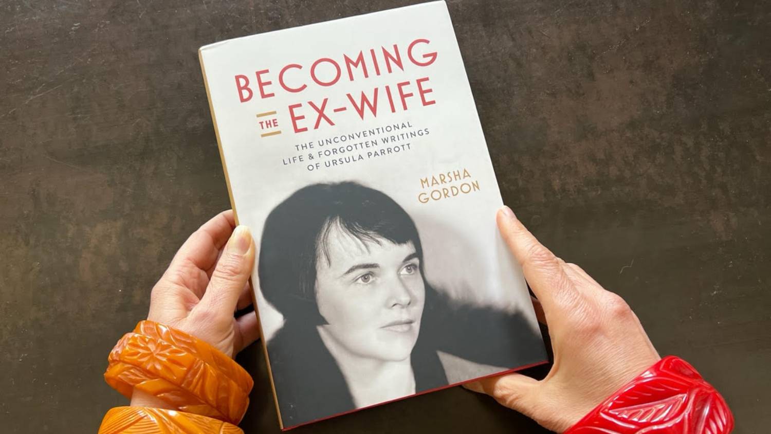 Two hands hold a copy of Marsha Gordon's book, "Becoming the Ex-Wife"