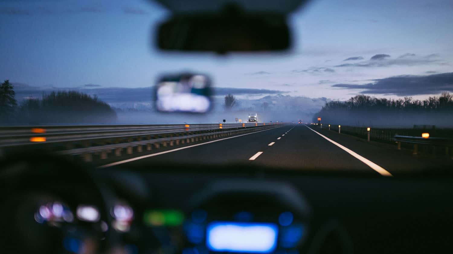 A vehicle drives on a foggy road.
