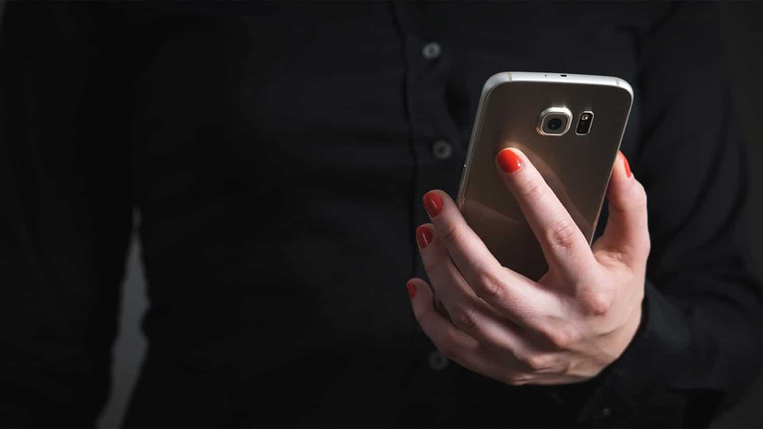 A hand holds a mobile phone.