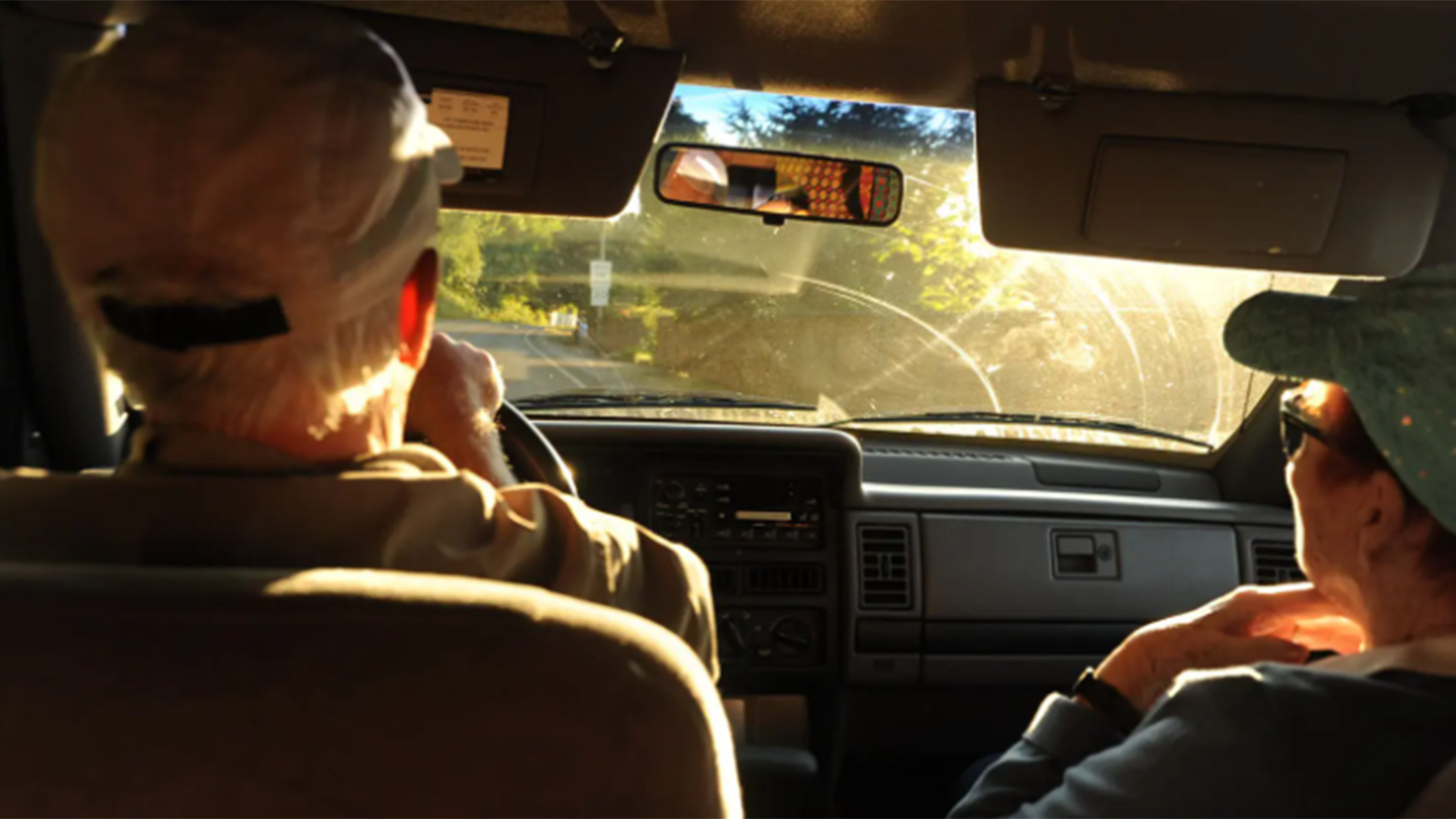 older man and woman driving in car