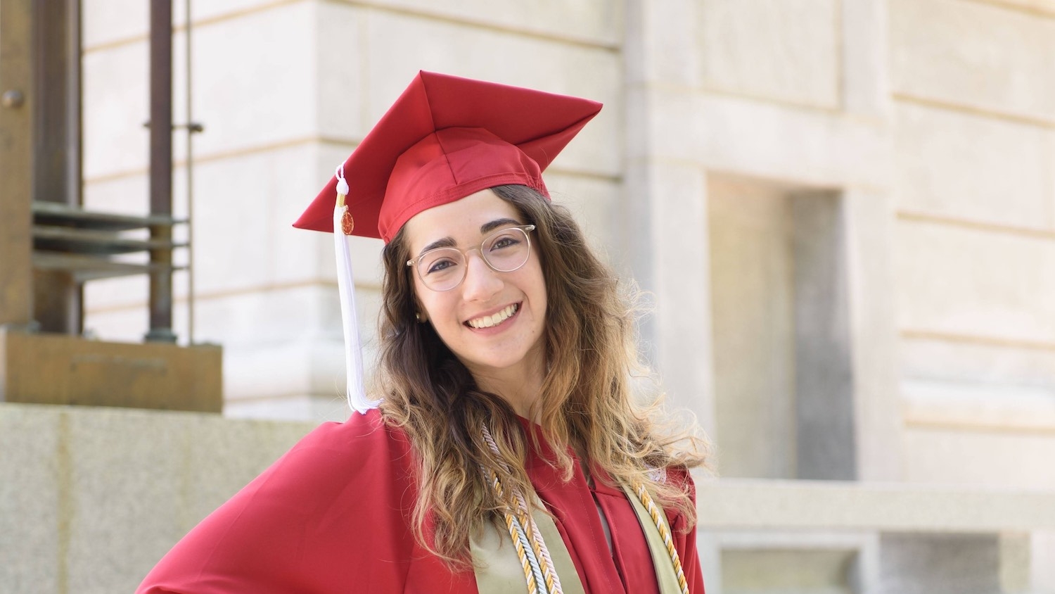 Lara Rabinowitz in her graduation cap and gown in front of the Memorial Belltower at Henry Square.